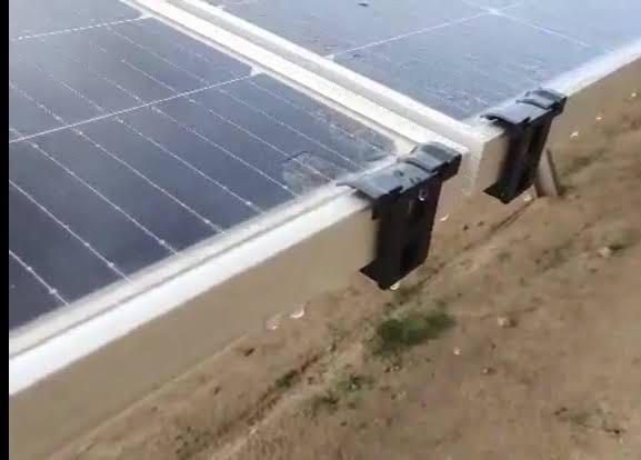 Two dark gray solar clips attached to two separate solar panels, securing them in place.