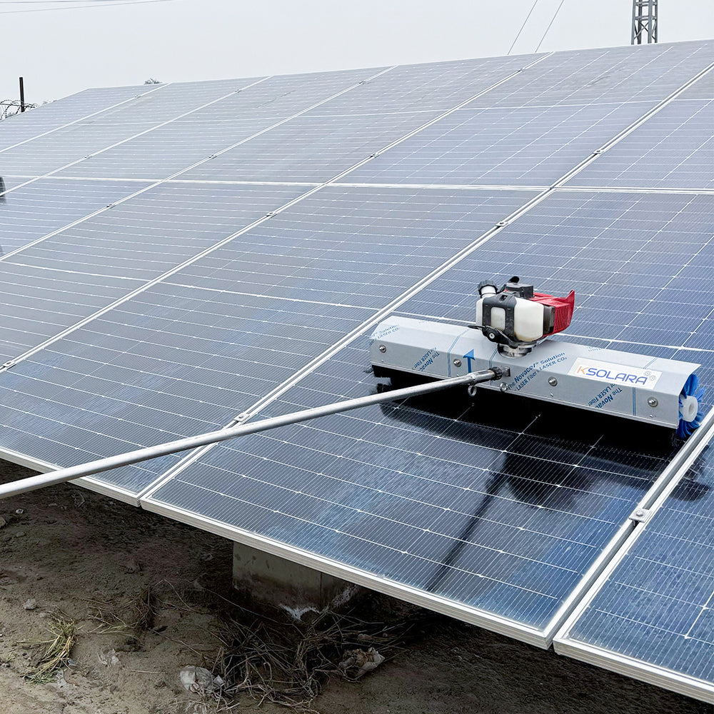 Silver steel solar cleaning robot with blue rotating brush gliding over a solar panel to remove dust and debris