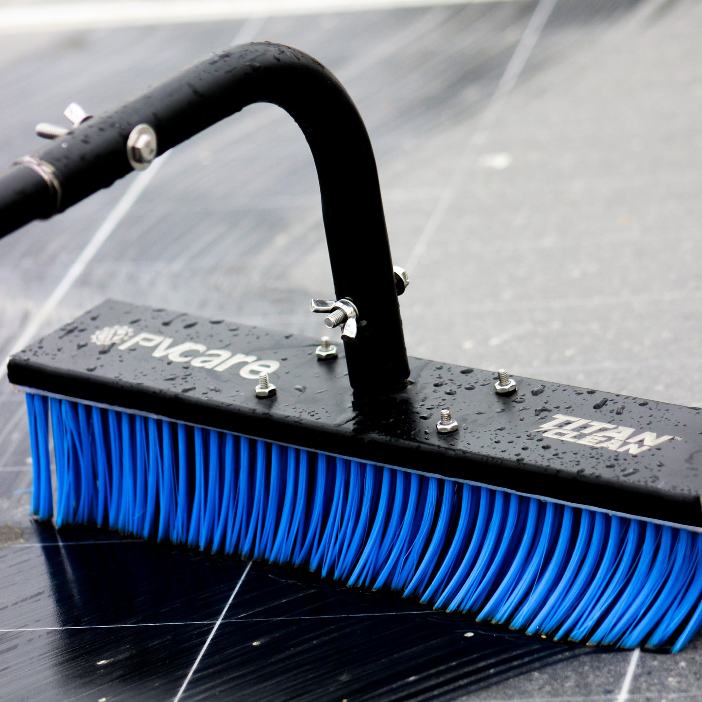 Solar Cleaning brush with blue bristles and black handle on a reflective surface